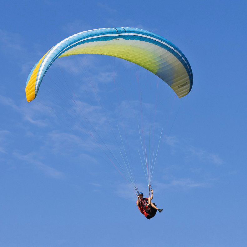Paragliding beneath a blue and yellow wing